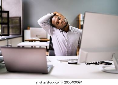 Employee Stretching At Office Desk At Work