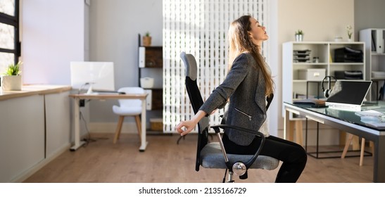 Employee Stretching At Office Desk At Work