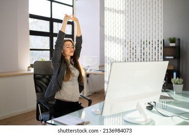 Employee Stretching At Office Desk At Work