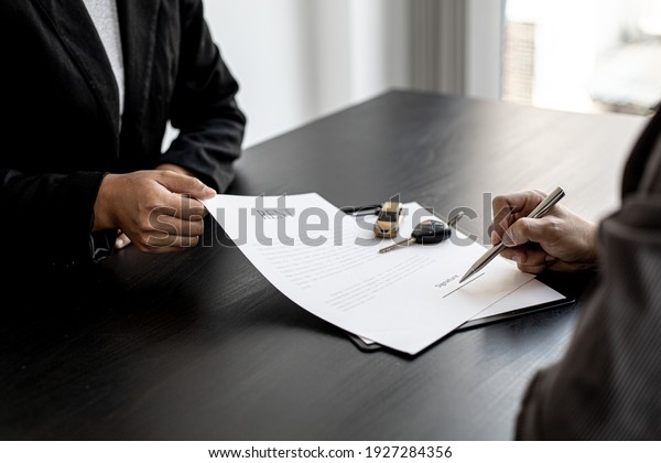 An employee submits a car rental agreement\
for the renter to sign the rental agreement after discussing the\
rental details. Concept of car\
rental.