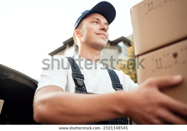 Employee in uniform logistics company. \
Delivery of a box of products and goods to your home. Fast delivery\
of the goods. The driver of the courier\
service.