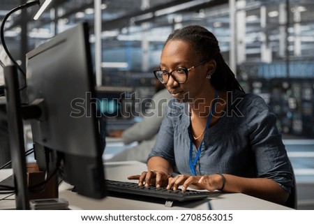 Employee using PC to oversee data center equipment providing processing resources for different workloads. Admin doing maintenance on server rigs tasked with solving complex operations