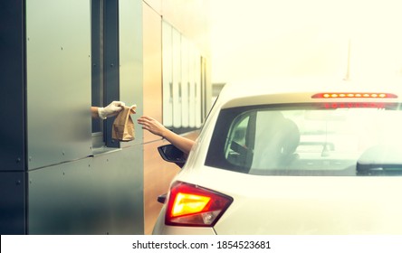 Employee wearing gloves delivers take out food out the window. Shopping for food from the car. Pick up fast food from the counter. Concept of social distance and new normality.