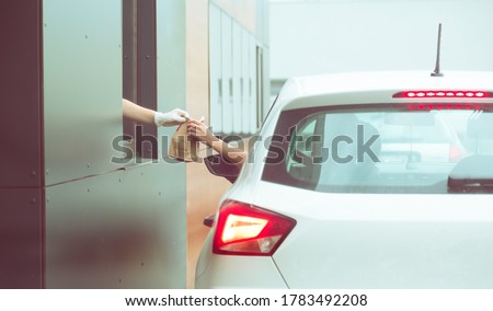 Employee wearing gloves delivers take out food out the window. Shopping for food from the car. Pick up fast food from the counter. Concept of social distance and new normality.
