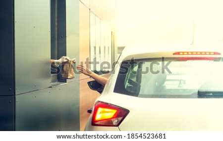 Employee wearing gloves delivers take out food out the window. Shopping for food from the car. Pick up fast food from the counter. Concept of social distance and new normality.

