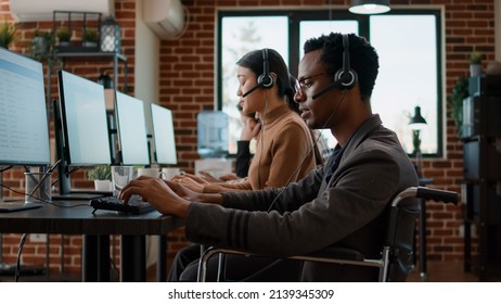 Employee With Working At Customer Care Service To Give Support To People Needing Help. Man In Wheelchair Sitting At Call Center Workstation To Talk To Clients About Telemarketing.