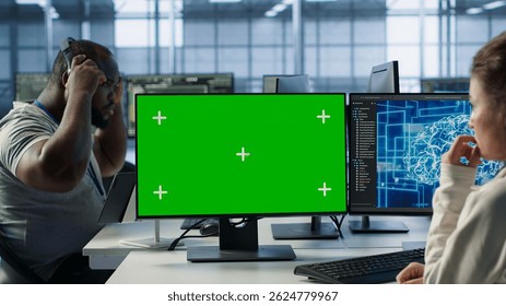 Employee working on green screen computer in server hub, using AI to process data. IT developer at chroma key PC updating servers controlling network resources using artificial intelligence, camera A