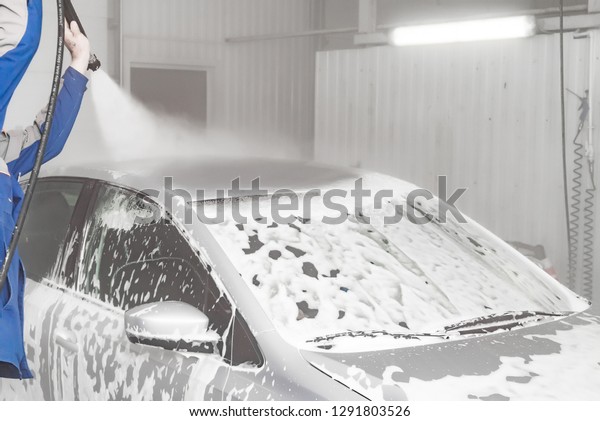 the employee works in the car wash. washing machine
with foam and water