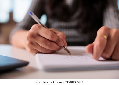 Employee Writing Information On Notebook, Taking Notes About Business Report On Textbook At Home. Working On Startup Paperwork And Attending Online Class Webinar On Computer. Close Up.