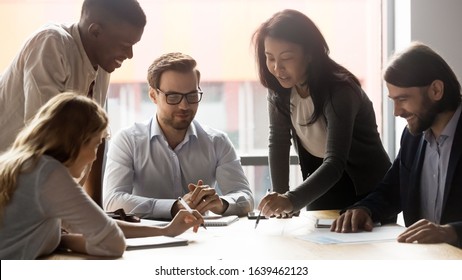 Employees with confident team leader working on new project at meeting, diverse business people discussing strategy, sharing startup ideas, checking documents, statistics, engaged in teamwork