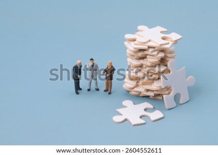 Employees are discussing to solve work problems. Miniature people with jigsaw puzzles stacked next to them