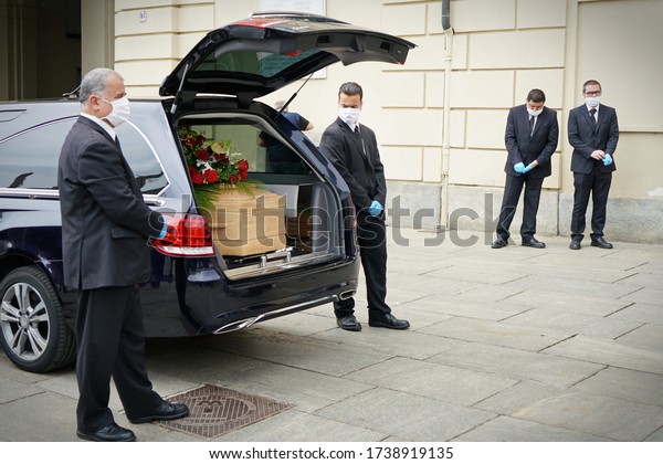 Employees of the\
funeral services company next to the coffin of a COVID-19 victim,\
in Turin, Italy, April\
2020.