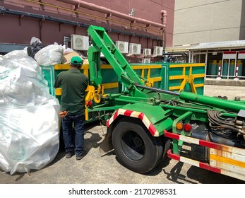 Employees with green trucks for transporting garbage. Urban waste recycling service