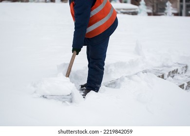 Employees of municipal services in a special form are clearing snow from the sidewalk with a shovel. - Shutterstock ID 2219842059