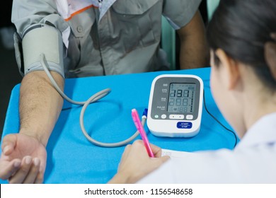 Employees And Nurse Use Blood Pressure Monitor, Annual Health Check In Factory