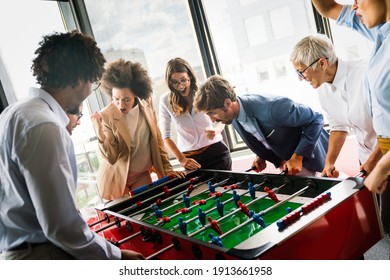 Employees playing table soccer indoor game in the office during break time