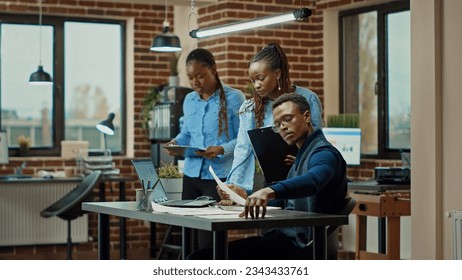 Employees reading annual data in office, examining official information on papers to increase company profit. Colleagues team planning new research project with results and analytics.