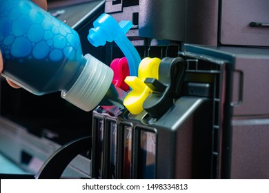 Employees refilling ink into a ink tank printer at home office. Hand holding blue ink cartridge and insert to the printer. - Shutterstock ID 1498334813