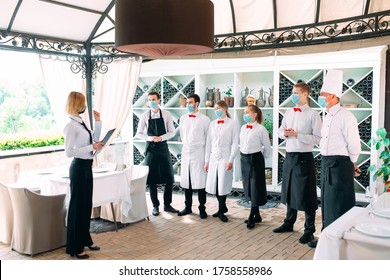 Employees Of A Restaurant Or Hotel In Protective Masks. End Of Quarantine. Restaurant Manager And His Staff On The Terrace. Interaction With The Chef In The Restaurant