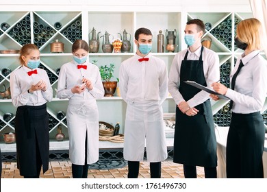 Employees Of A Restaurant Or Hotel In Protective Masks. End Of Quarantine. Restaurant Manager And His Staff On The Terrace. Interaction With The Chef In The Restaurant