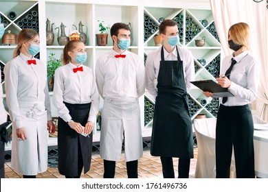 Employees Of A Restaurant Or Hotel In Protective Masks. End Of Quarantine. Restaurant Manager And His Staff On The Terrace. Interaction With The Chef In The Restaurant