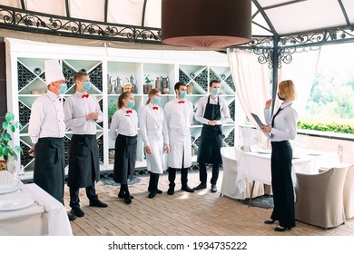 Employees Of A Restaurant Or Hotel In Protective Masks. End Of Quarantine. Restaurant Manager And His Staff On The Terrace. Interaction With The Chef In The Restaurant