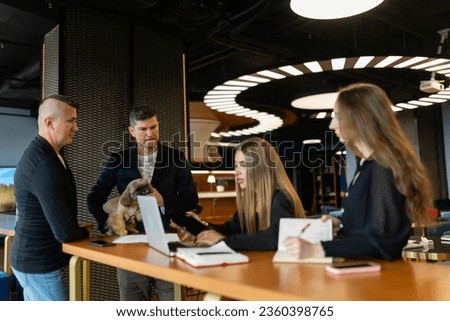 Employees settle work issues in conference room accompanied by Shih Tzu. Colleagues listen and actively take notes during discussion