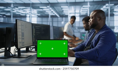 Employees using green screen laptop, working in server farm to optimize it for data processing requirements. Close up of mockup notebook on desk next to workers coding in data center, camera A - Powered by Shutterstock - Get 15% off with code: PIKWIZARD15