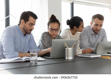 Employees working at computer together, discussing content. Intern learning new skills from mentor. Diverse millennial business colleagues sharing laptop. Teamwork, corporate education concept