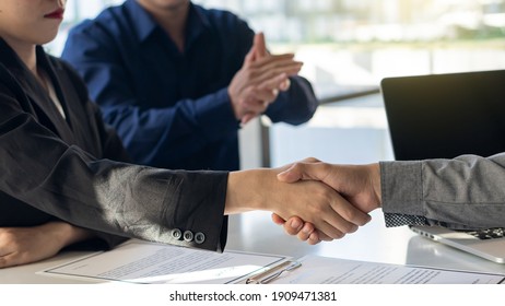 The employer shook hands to congratulate the new employee in the interview after meeting in the office with a friend clapping and rejoicing at the job interview idea.