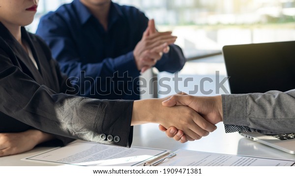 The employer shook
hands to congratulate the new employee in the interview after
meeting in the office with a friend clapping and rejoicing at the
job interview idea.