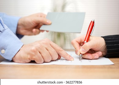 employer shows employee where to sign and giving her booklet at the same time