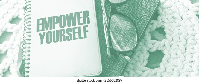 Empower Yourself words on book cover with eyeglasses and pen. Business motyvation concept.