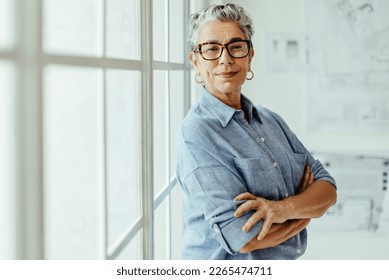 Empowered female designer standing in her office and looking at the camera. She is a mature and confident business woman with experience and expertise in her work as a design architect. - Shutterstock ID 2265474711