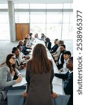 An empowered woman leader addressing a diverse group of colleagues in a professional meeting held in a contemporary office environment.