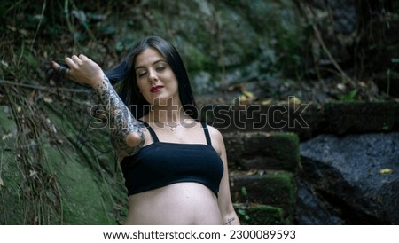Empowered young pregnant Caucasian Brazilian pregnant woman Mother with tattoo looking towards one direction in mysterious abandoned scenery during daytime in summer