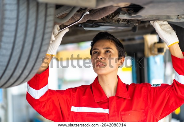 Empowering Caucasian woman\
mechanic wearing red uniform working Under a Vehicle in a Car\
Service station. Expertise mechanic working in automobile repair\
garage.