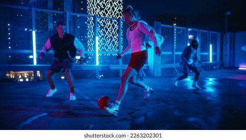 Empowering Sporty Young Woman Playing Soccer with Friends, Dribbling, Scoring a Successful Goal. Female Footballer Playing Football Outside at Night on Rooftop Urban City Spot with Neon Lights - Powered by Shutterstock