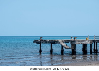 An empty abandoned dock with blue sea under the blue sky in the background.  - Powered by Shutterstock