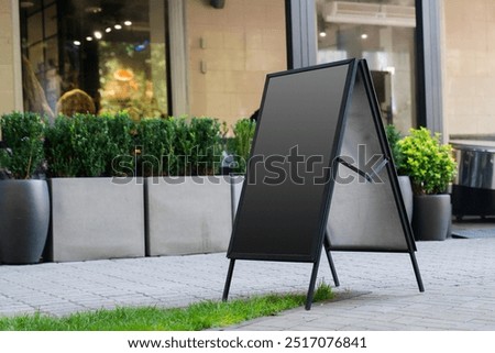 Empty A-frame sidewalk sign placed on city street, perfect for customizable advertising in front of a shop or café.