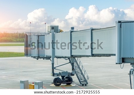 Empty aircraft parking passenger air bridge at airport apron against the backdrop of a beautiful sky