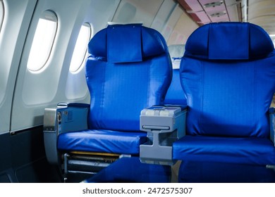An empty airplane cabin awaits passengers for journey. Rows of seats line the interior, illuminated by soft light filtering through windows.