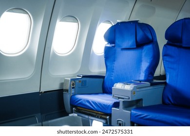 An empty airplane cabin awaits passengers for journey. Rows of seats line the interior, illuminated by soft light filtering through windows.