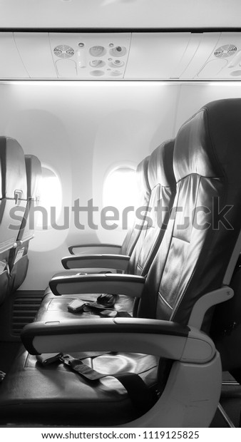 Empty airplane seat with light from the window in\
black and white filter.