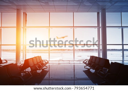 Empty airport terminal lounge with airplane on background. Sunset colors