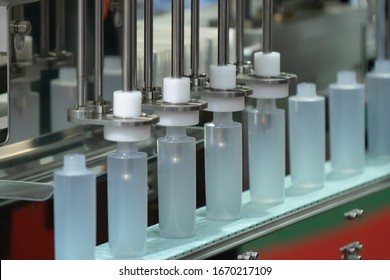 Empty Alcohol Gel Bottles transfer on Conveyor Belt System of Gel filling machine in an industry. White bottle moving on filling machine in a factory.