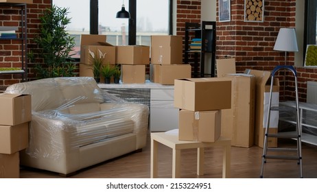 Empty Apartment Flat Full Of Moving Unpacked Cardboard Boxes, Storage Packages In Living Room. Relocation Concept In New Real Estate Property, Furniture In Carton Containers With No People.