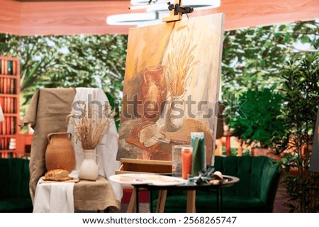 Empty art and craft workshop with a rustic beautiful painting on canvas, creative work with watercolor paint in a modern contemporary atelier. Artistic masterpiece with paint tubes and tools.