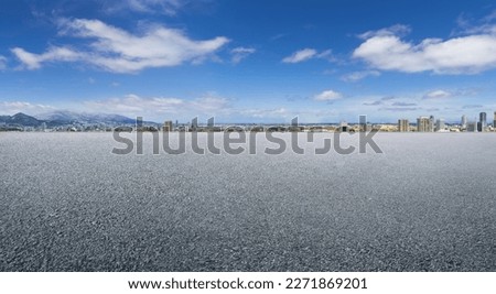 Empty asphalt floor with faraway cityscape background