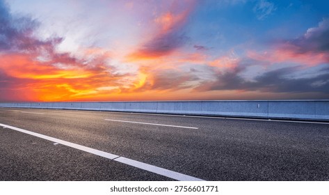 Empty asphalt highway under a dramatic and colorful sunset sky with vibrant clouds 